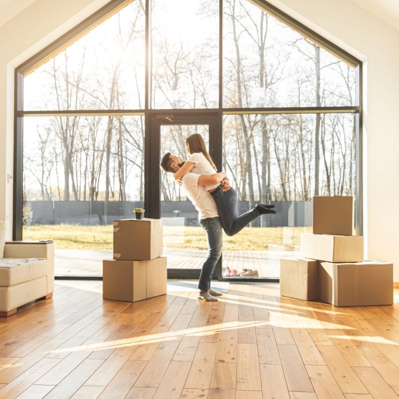 young couple moves to a new home. the family carries boxes of things after buying a second mortgage toronto