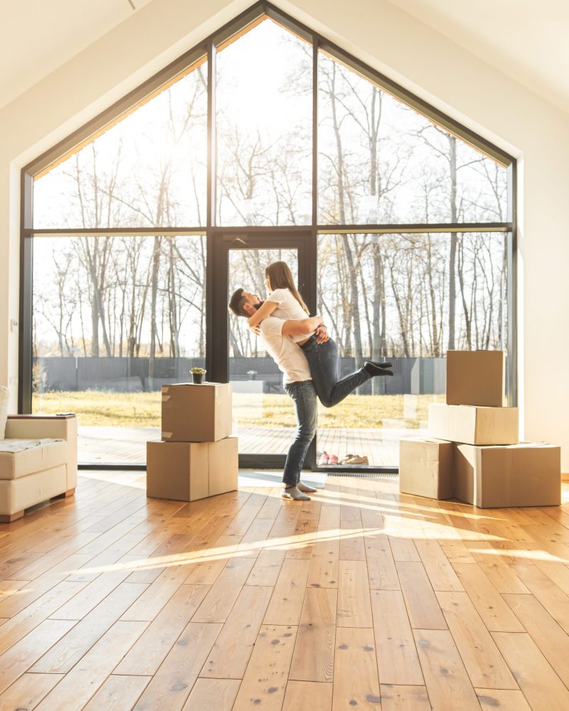 young couple moves to a new home. the family carries boxes of things after buying a second mortgage toronto